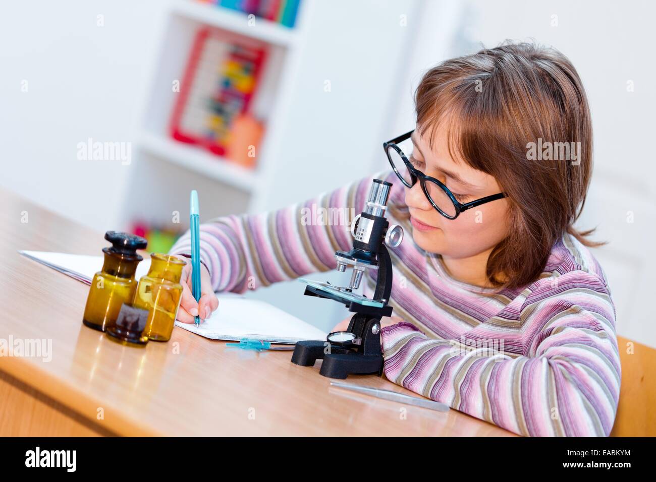 La science des ados fille sur le cours de biologie avec microscope et des échantillons, l'écriture de l'expérience résultats Banque D'Images