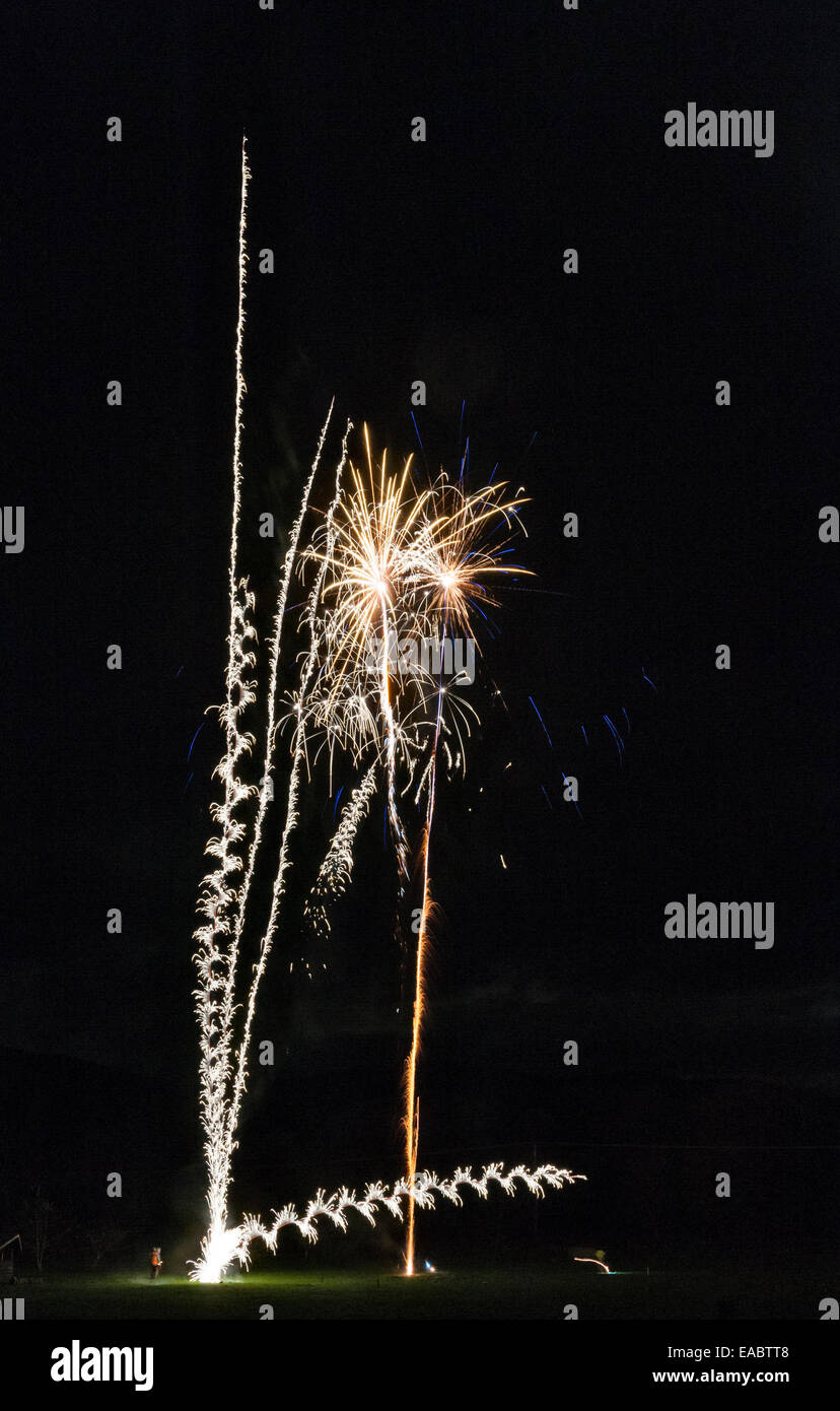 Homme lançant des feux d'artifice sur un feu d'artifice de village, avec une fusée se déplaçant dangereusement sur le côté (Royaume-Uni) Banque D'Images