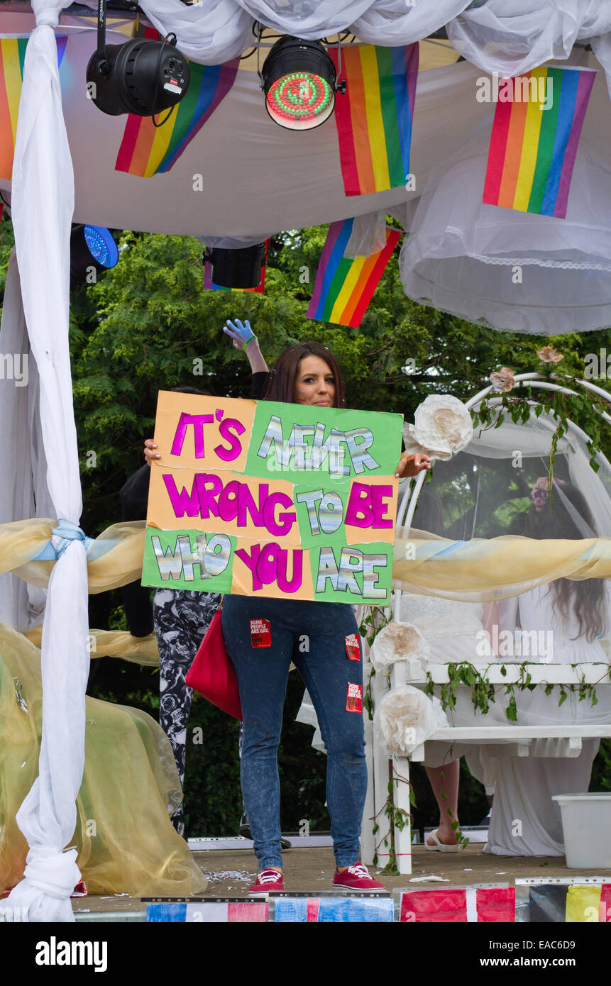 Northampton, Royaume-Uni ; carnaval haut en couleurs flotter avec Jeune femme tenant une pancarte disant 'il n'est jamais mauvais d'être qui vous êtes' Banque D'Images