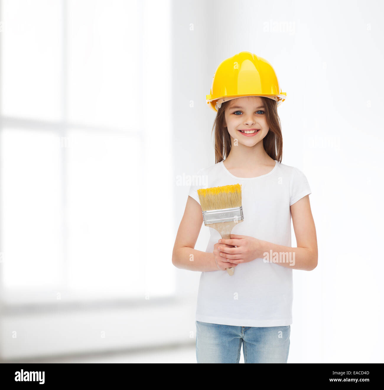 Smiling little girl in helmet with paint roller Banque D'Images