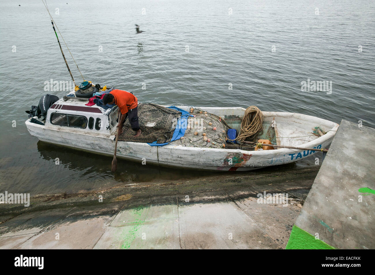 Manoeuvre pêcheur panga voile à l'aide d'un aviron en bois comme il docks le long du littoral, de la baie de Campeche, Campeche, Mexique Banque D'Images