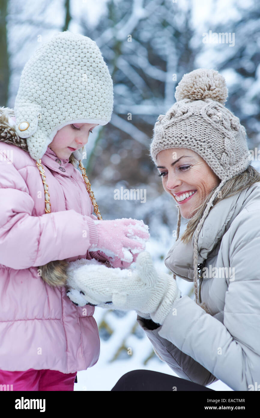 La mère et l'enfant à jouer ensemble dans la neige d'hiver Banque D'Images