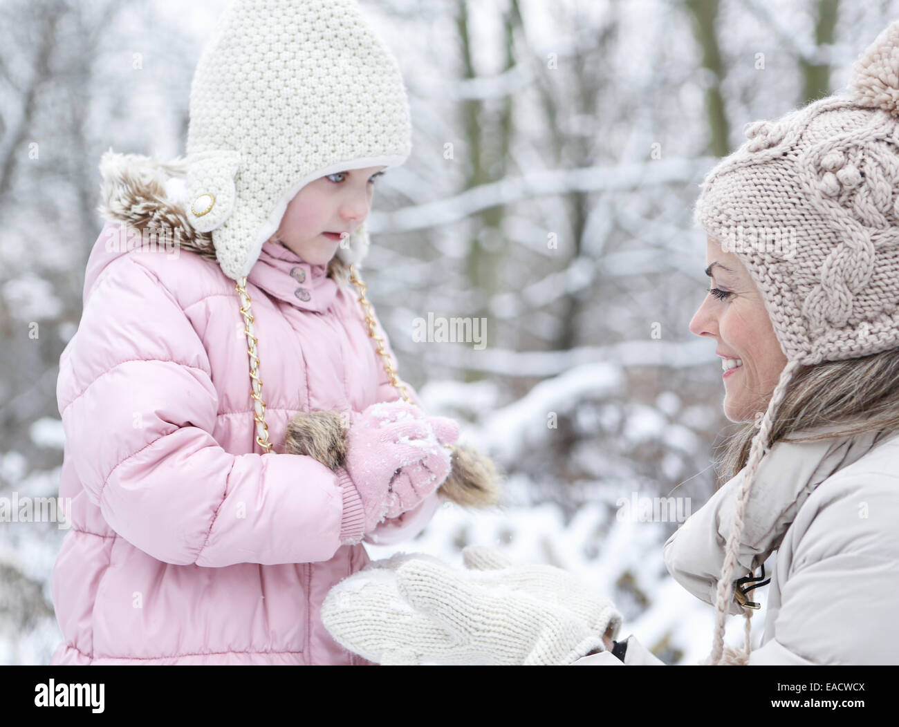 Happy mother and daughter formant un ensemble de boules de neige en hiver Banque D'Images