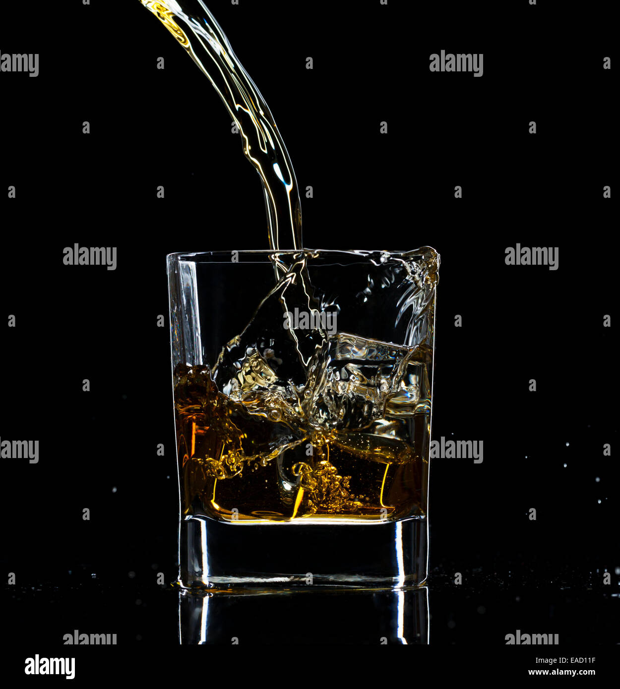 Verser dans un verre à whisky, isolé sur fond noir Banque D'Images