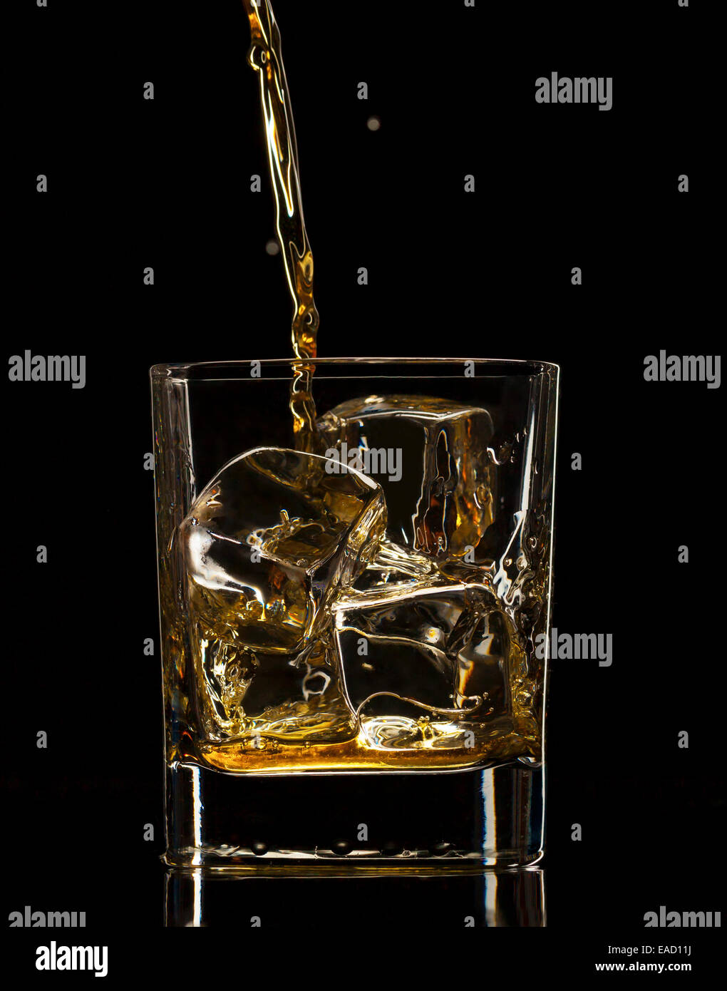 Verser dans un verre à whisky, isolé sur fond noir Banque D'Images