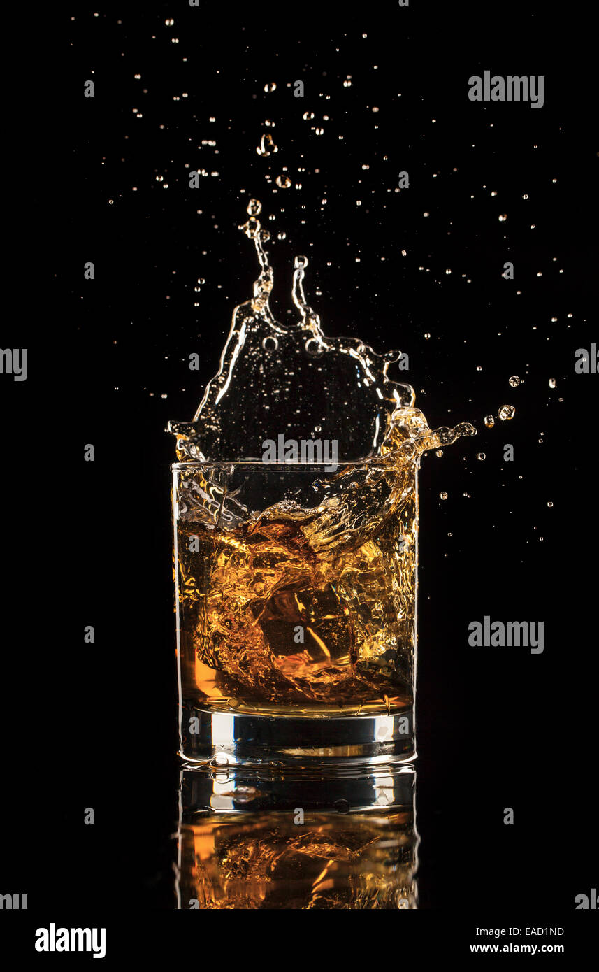 Shot de whiskey isolé avec splash sur fond noir Banque D'Images