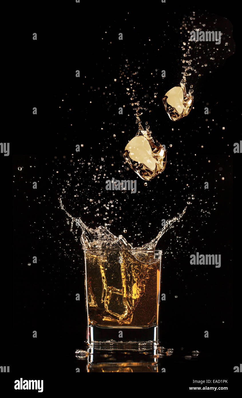Shot de whiskey isolé avec splash sur fond noir Banque D'Images