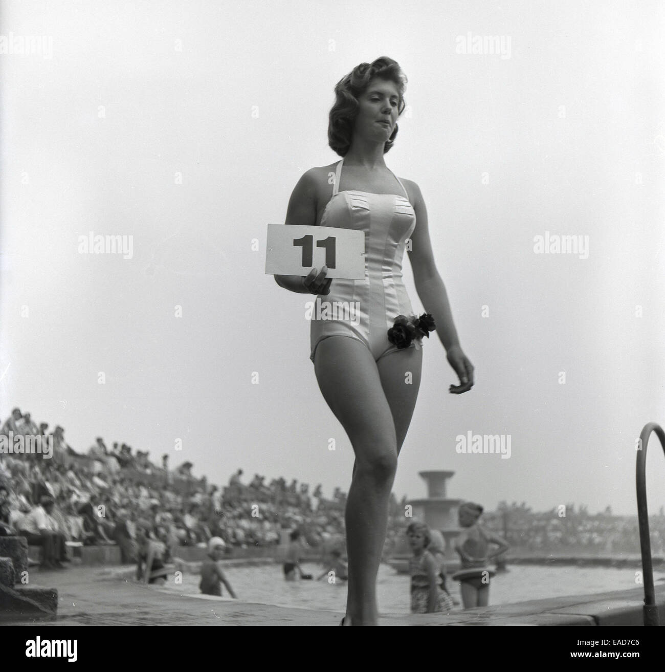 Historique, 1950, maillot de bain ou un concours de beauté, une femme tenant un concurrent numéro 11 sign in horizons passer une piscine. Banque D'Images