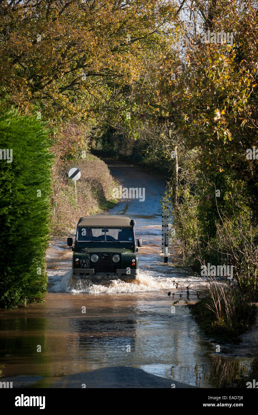 Un conducteur d'un Land Rover série II traverse des inondations près de Rewe, Exeter, Devon, Royaume-Uni, où le ponte fluvial a éclaté ses berges après de fortes pluies. Banque D'Images