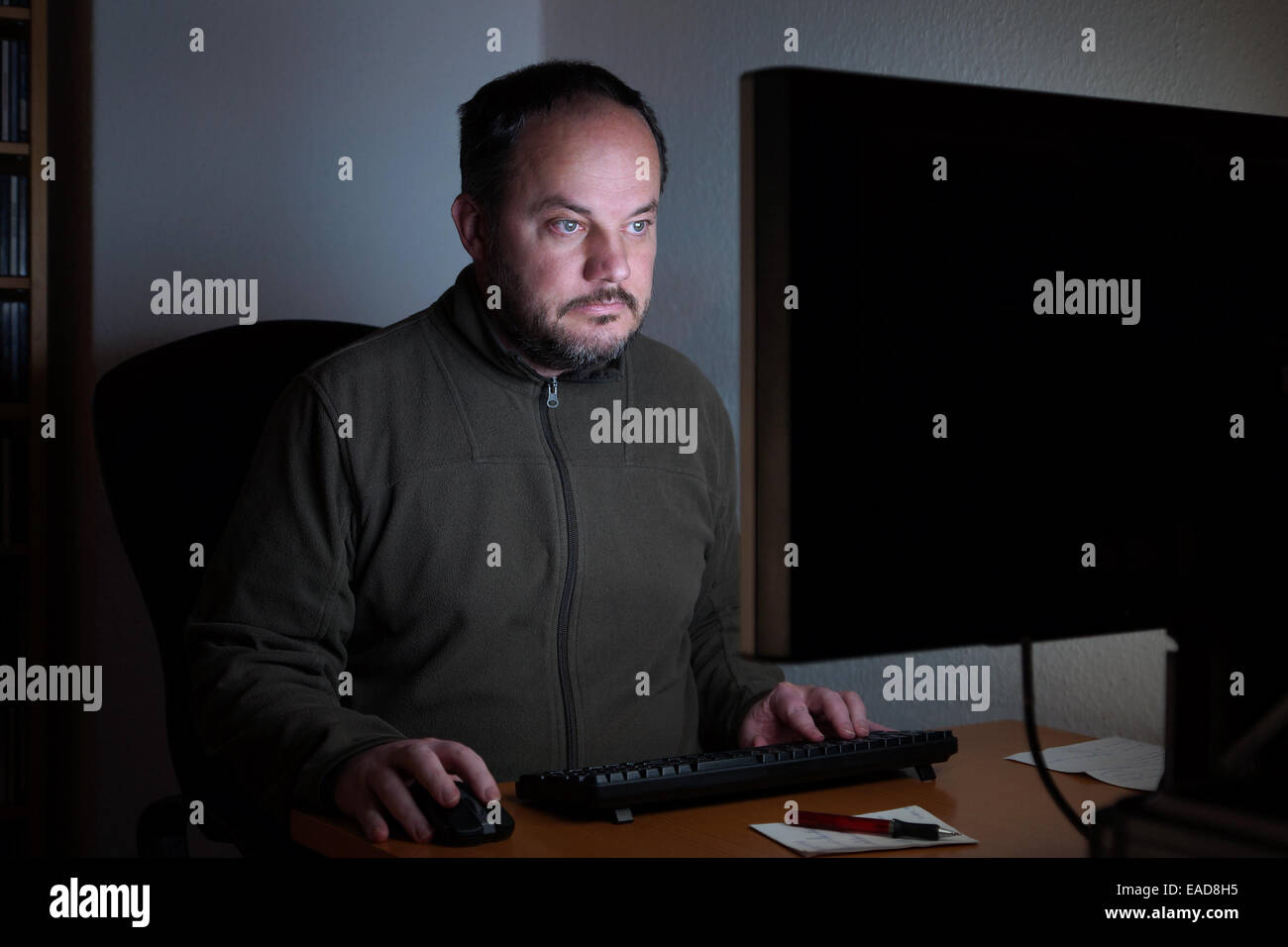 Homme assis en face de l'ordinateur à la nuit Banque D'Images