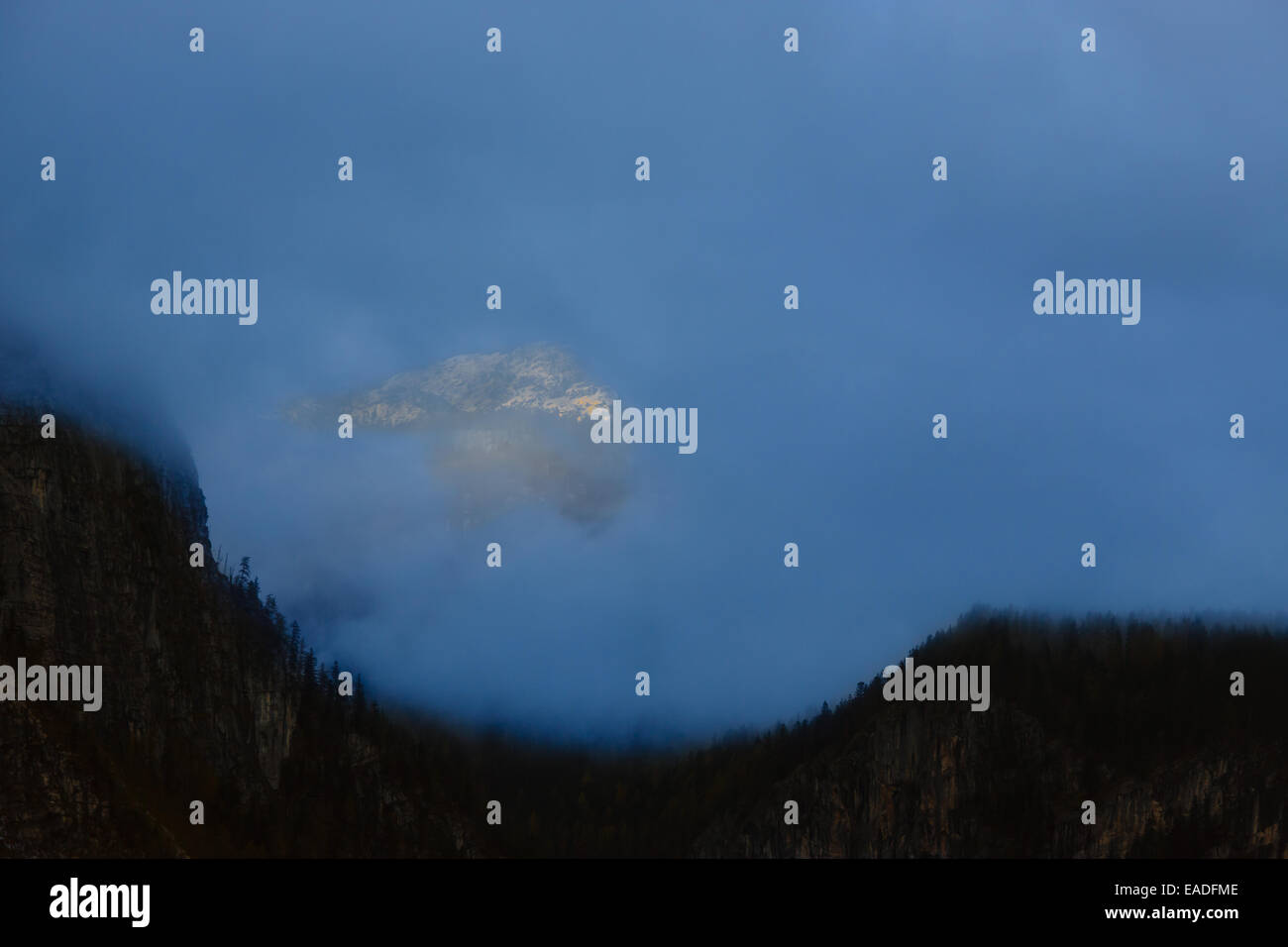 Sommet de montagne illuminée par des faisceaux d'un soleil qui se lève à l'écart des nuages Banque D'Images