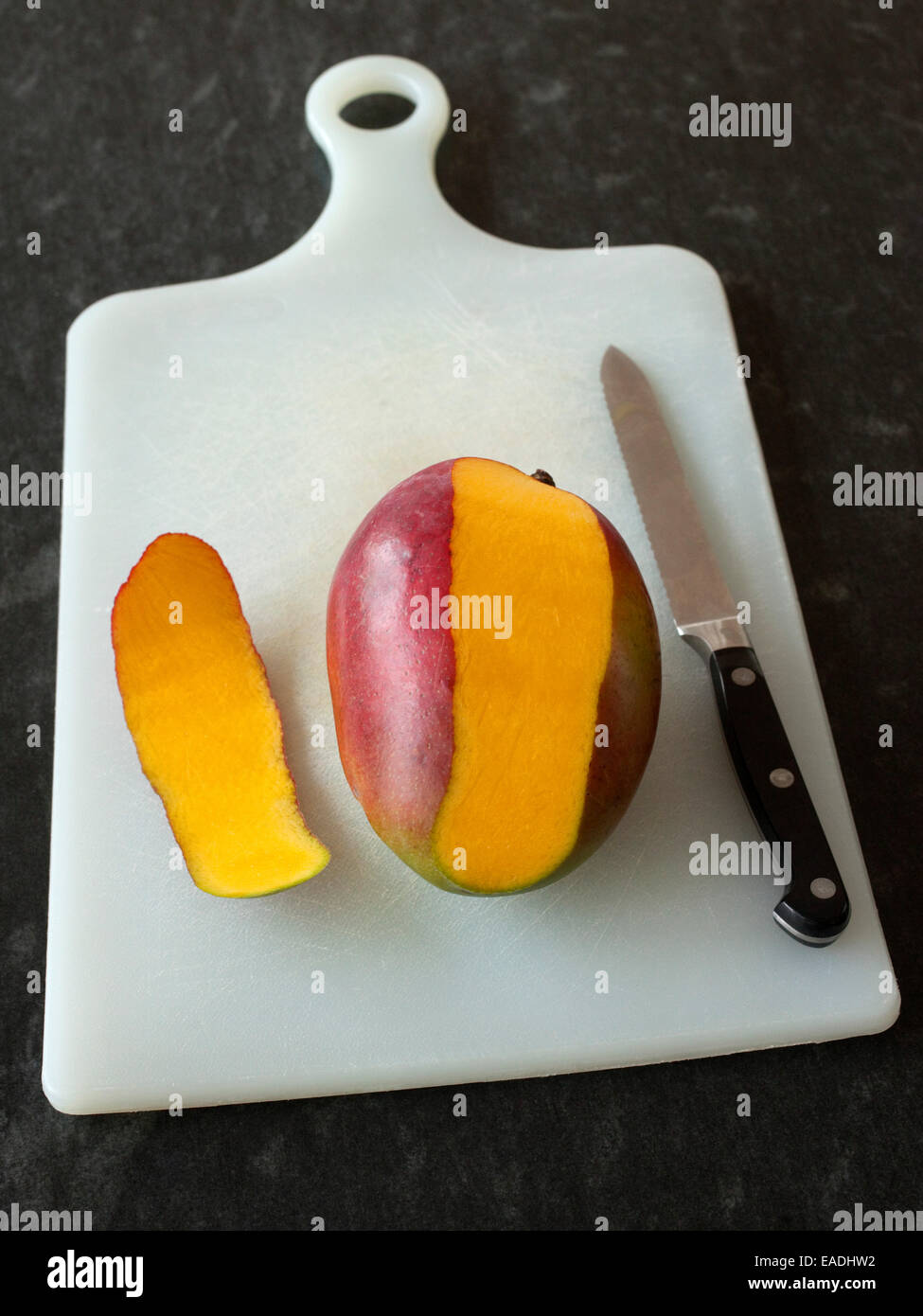 Mangue pelée partiellement et knife on cutting board Banque D'Images