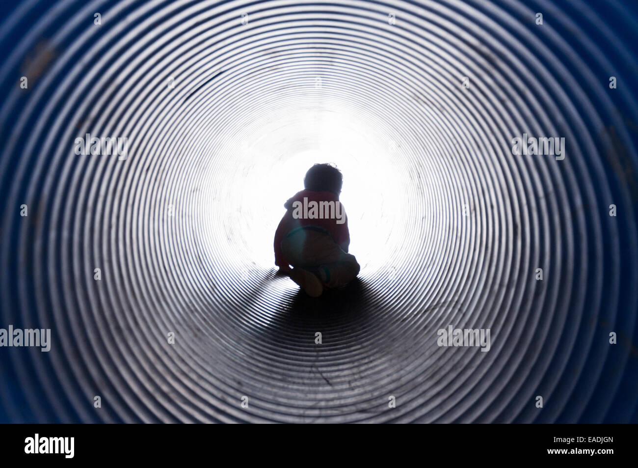 Garçon escalade à travers un tunnel avec la lumière au bout du tunnel Banque D'Images Garçon escalade à travers un tunnel avec la lumière au bout du tunnel Banque D'Images
