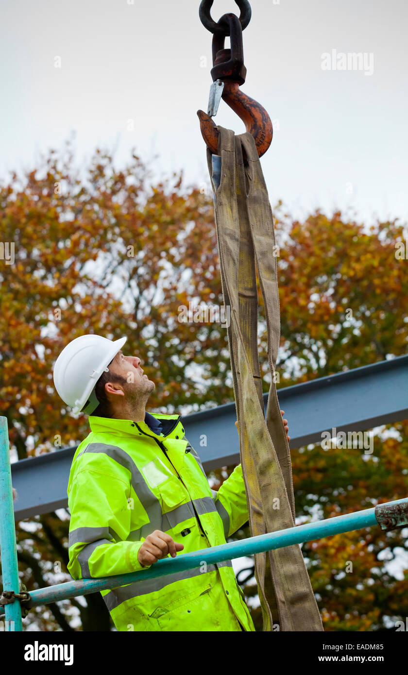 Builder travaillant sur un chantier de construction portant une veste haute visibilité et blanc casque casque de protection Banque D'Images