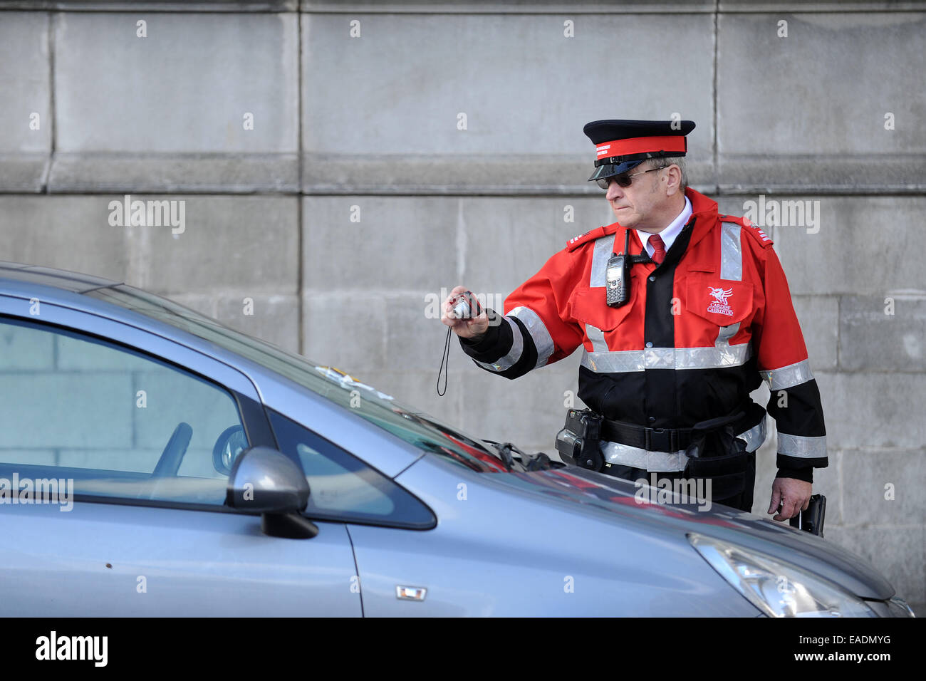 Un gardien de la circulation de photos une voiture après l'émission d'un ticket de parking pour stationnement illégal. Banque D'Images