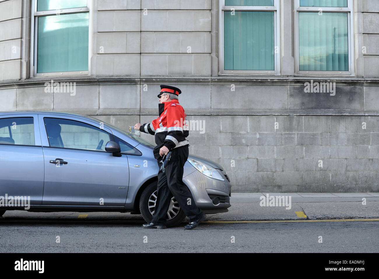 Un gardien de la circulation émet un ticket de parking pour une voiture en stationnement illégal. Banque D'Images
