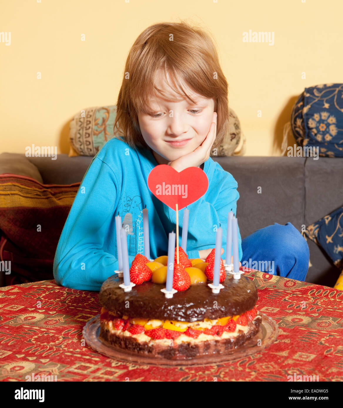 Garçon aux cheveux blonds regardant son gâteau d'anniversaire Banque D'Images
