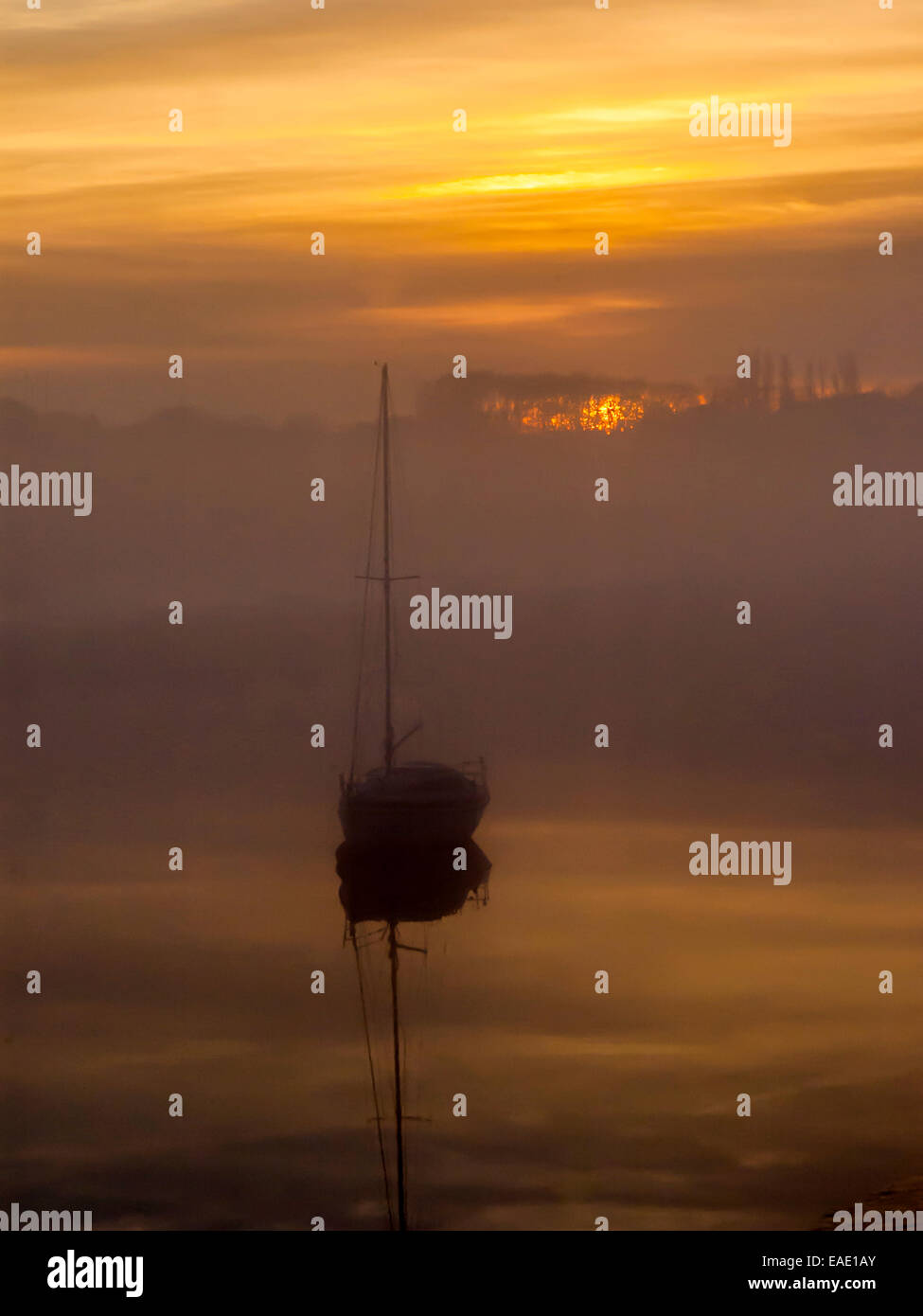 Coucher de soleil sur l'estuaire de Crouch représentant une toile de brume le long de la banque de réfléchir sur une rivière calme avec un petit bateau visible Banque D'Images
