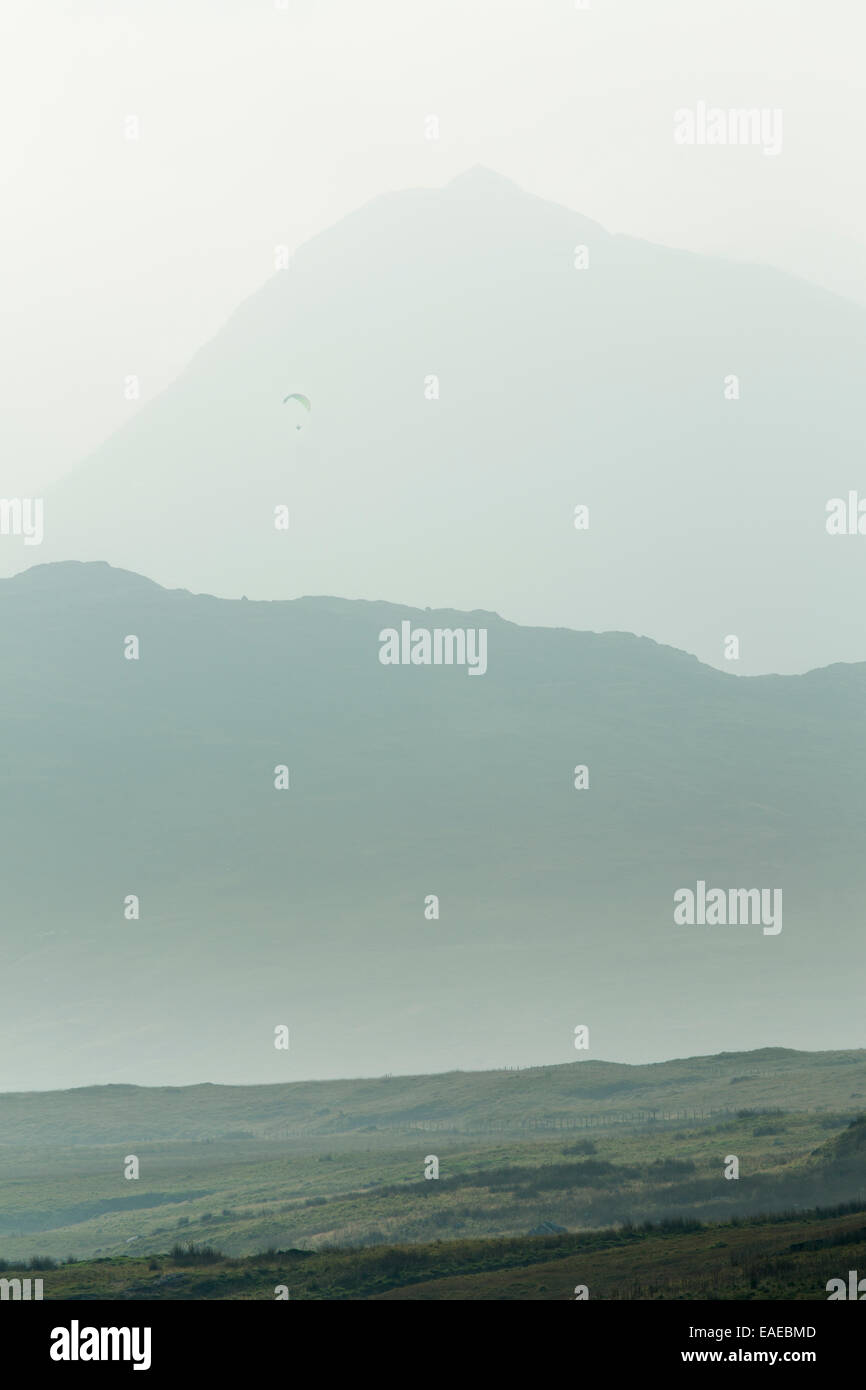 Un Parapente voiles au-dessus des montagnes couvertes de brouillard avec Snowdon en arrière-plan. Banque D'Images