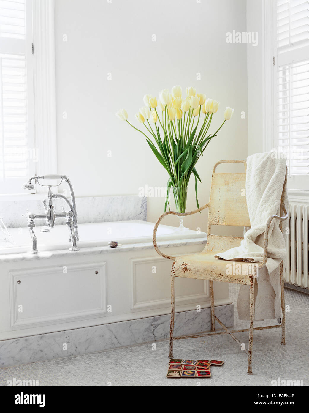 Shabby chic moderne salle de bains en marbre blanc, tulipes blanches et vieux fauteuil de jardin Banque D'Images