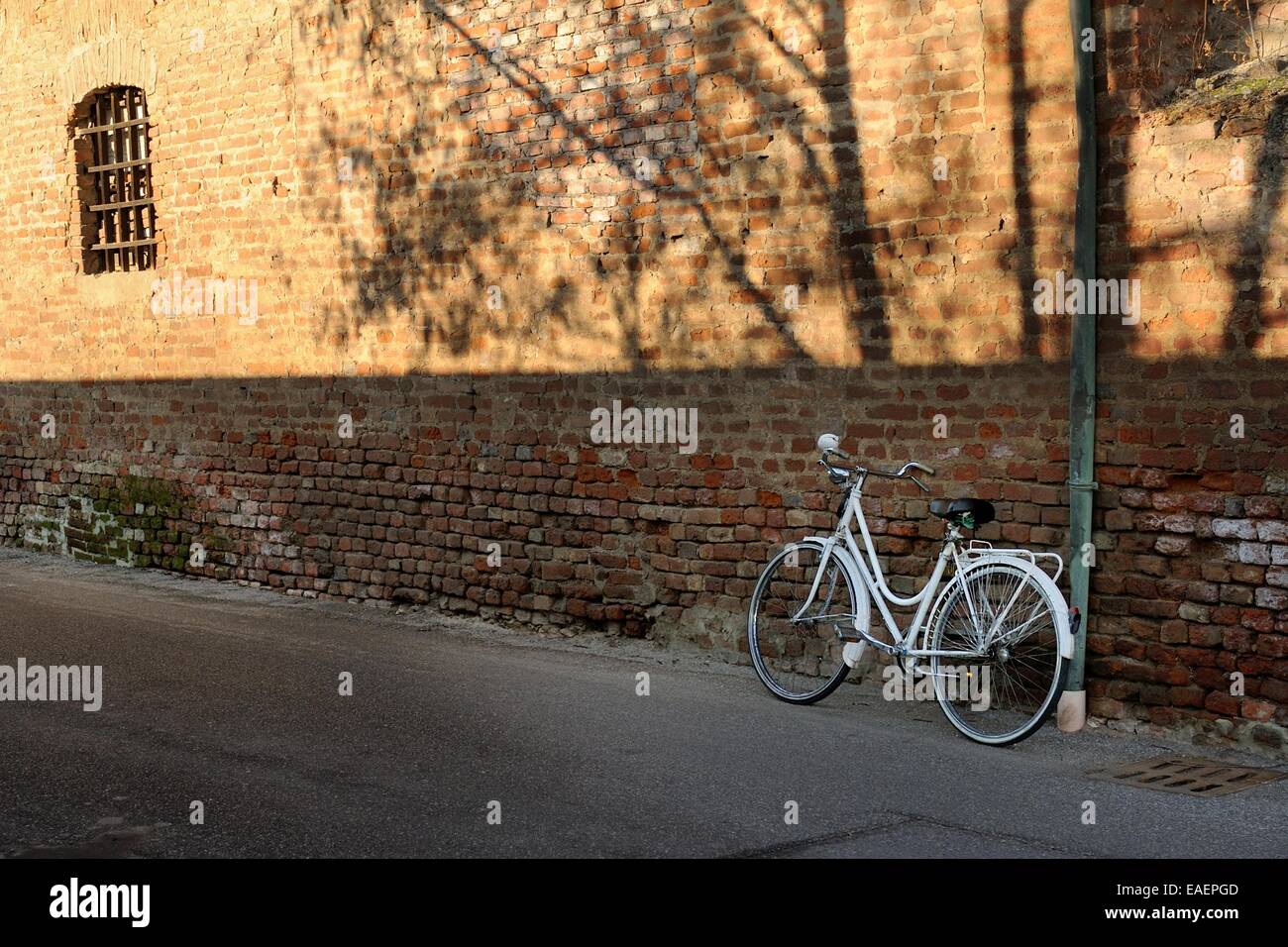 Vélo blanc garé dans un mur de briques Banque D'Images