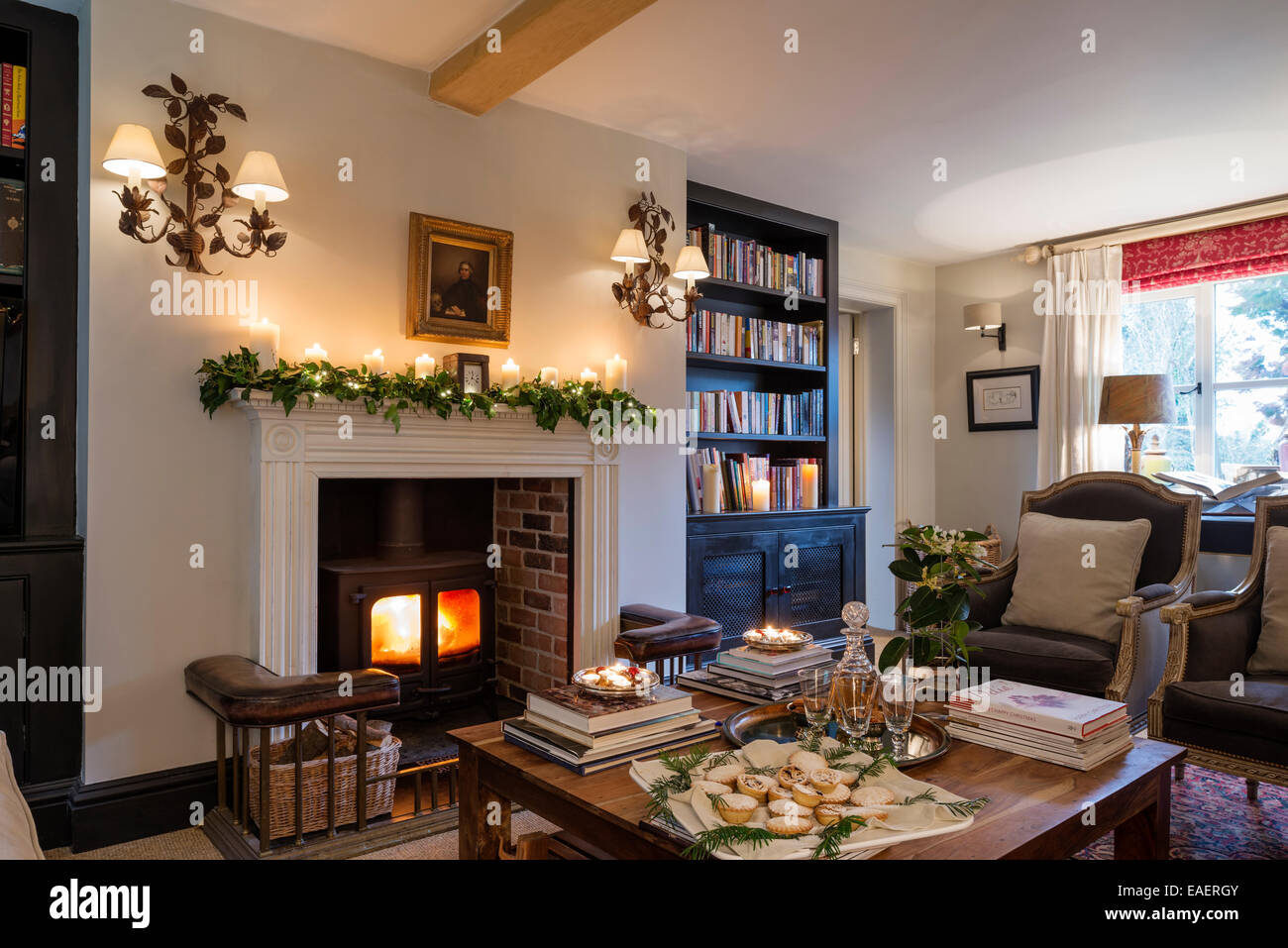 Poêle à bois avec le Georgian fire le surround dans salon avec paire de fauteuils par Andrew Martin. La paire de branche de chêne wal Banque D'Images