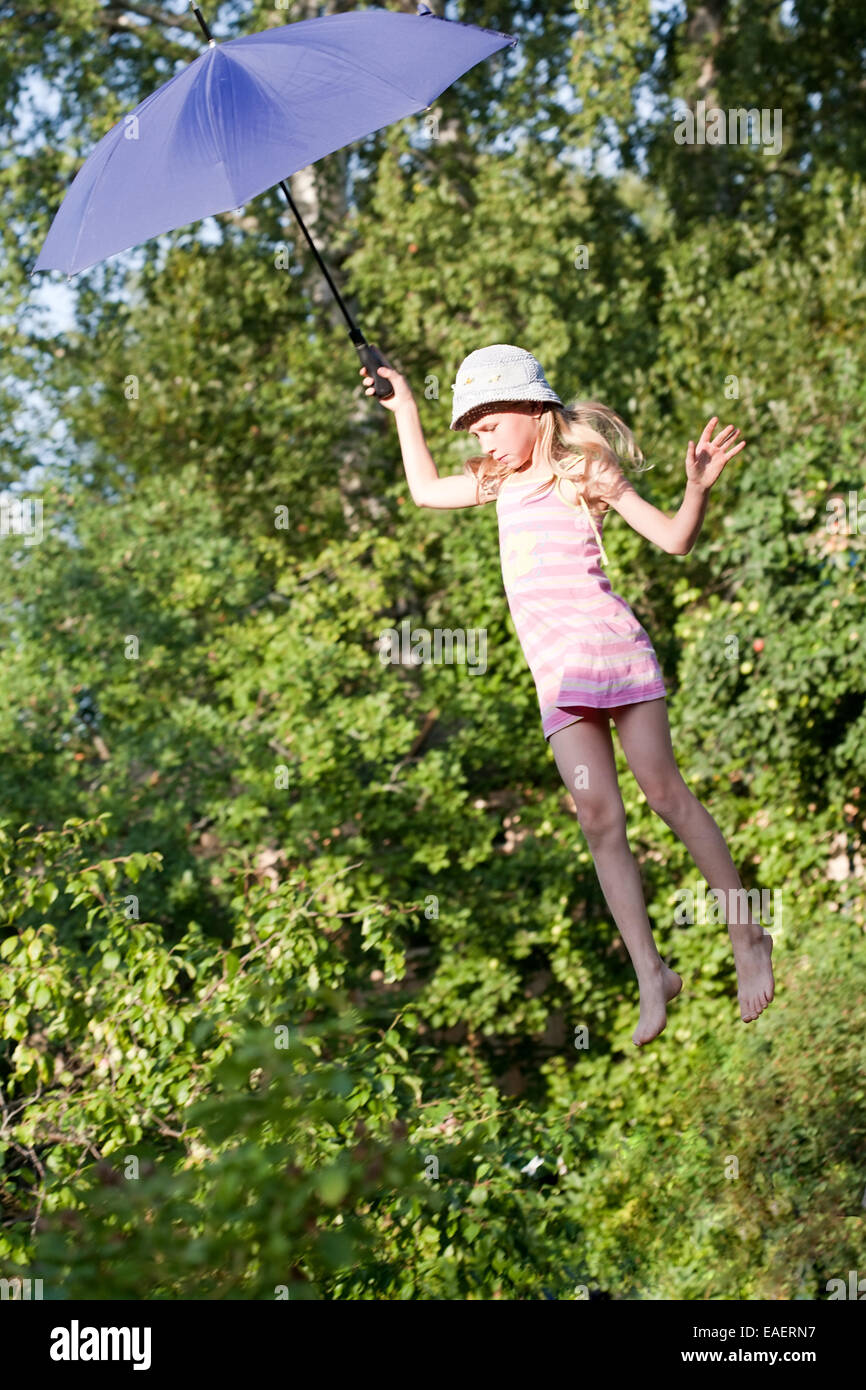 Petite fille battant avec parapluie bleu au-dessus du jardin d'arbres Banque D'Images
