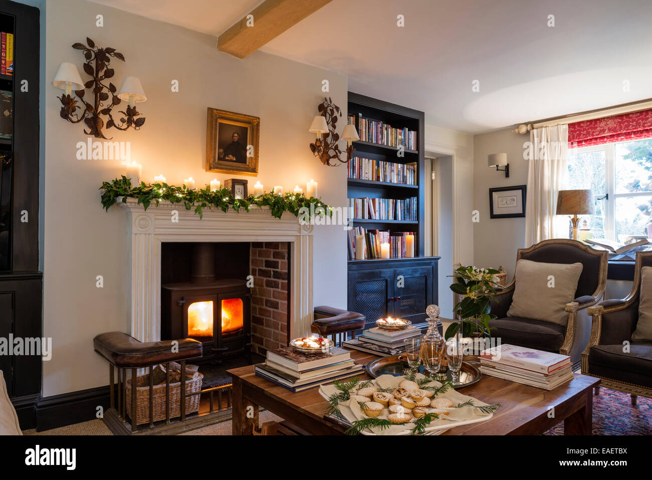 Poêle à bois avec le Georgian fire le surround dans salon avec paire de fauteuils par Andrew Martin. La paire de branche de chêne wal Banque D'Images