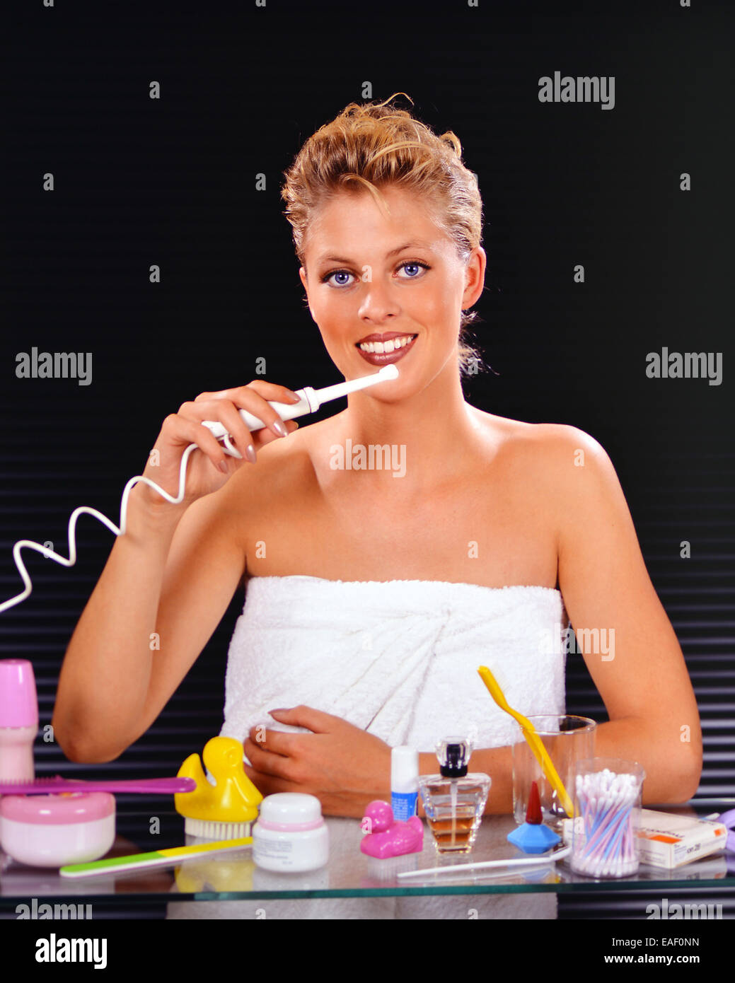 Femme blonde se brosser les dents avec une brosse à dents électrique Banque D'Images