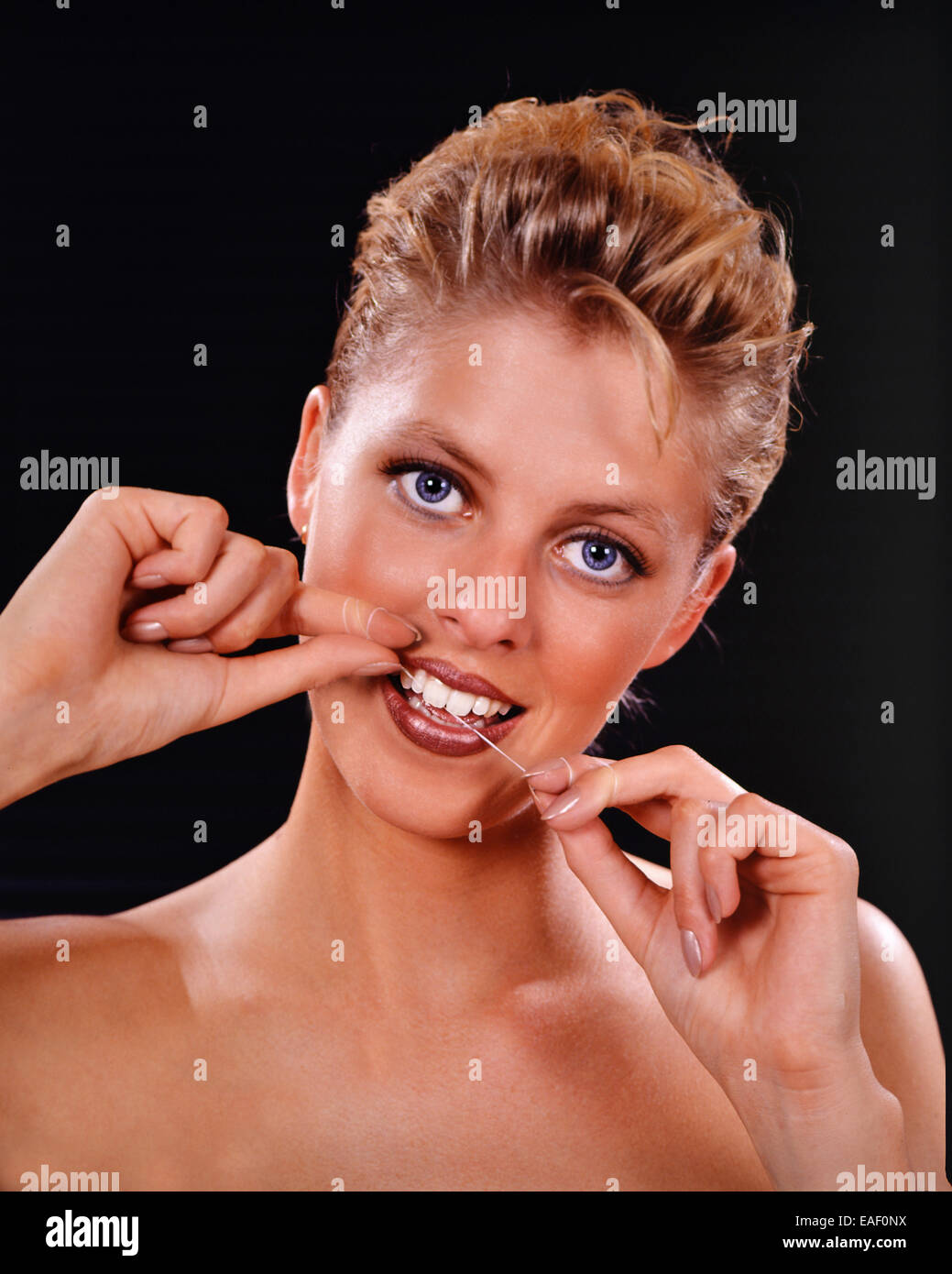 Femme blonde nettoyer les dents avec un fil dentaire Banque D'Images