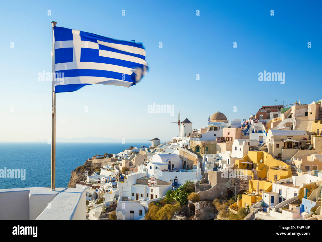 Drapeau grec au-dessus du village de Oia, Santorin, Santorini, Cyclades, îles grecques, Grèce, Union européenne, Europe Banque D'Images
