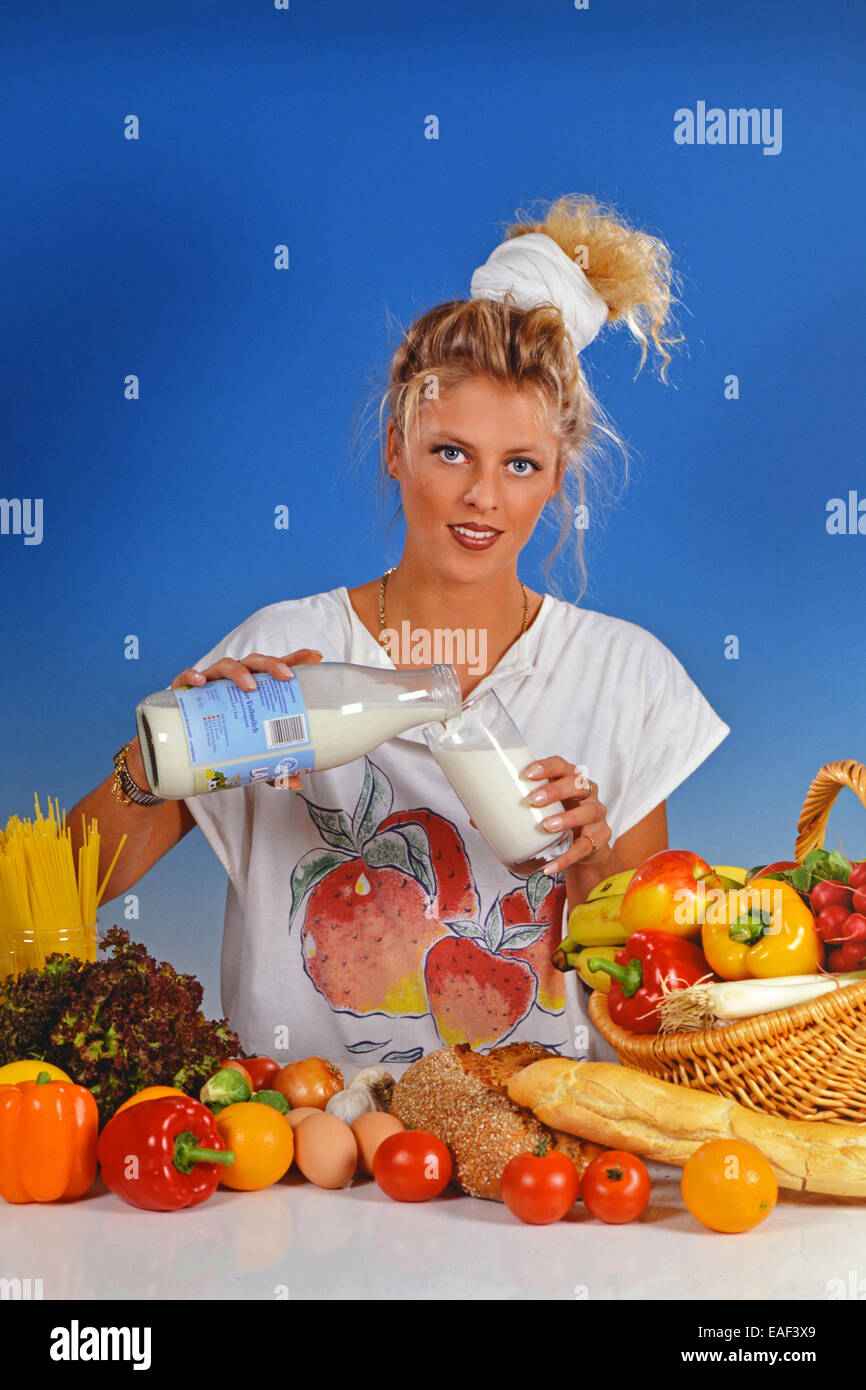 Blonde femme remplie de lait dans un verre Banque D'Images