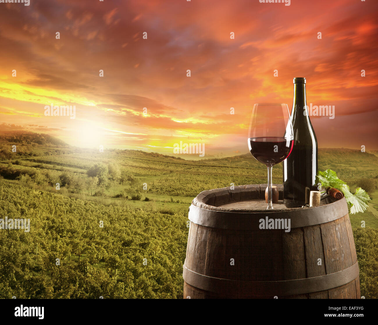 Poster encadré Verre et bouteille de vin rouge sur tonneau en bois avec  scène de vignoble 