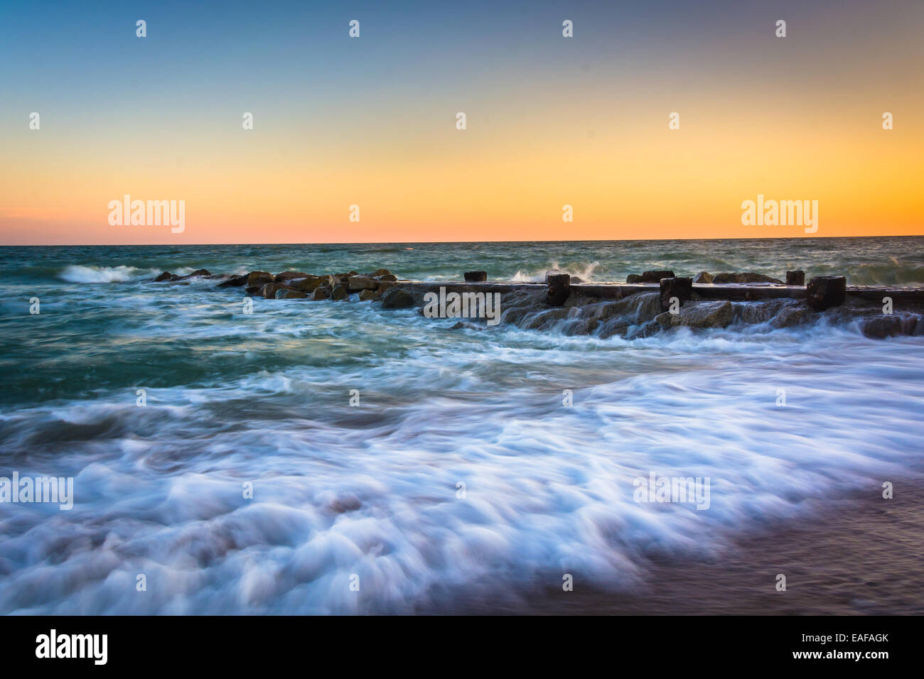 Les vagues et une jetée au coucher du soleil dans l'océan Atlantique à Edisto Beach, en Caroline du Sud. Banque D'Images