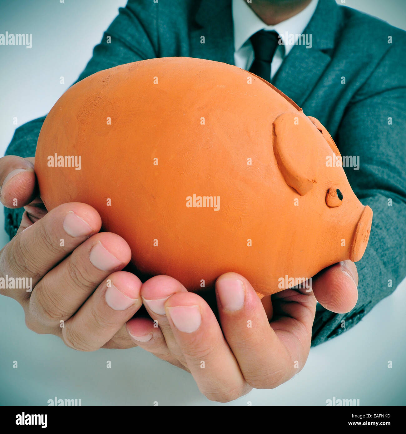 Un homme portant un costume holding a piggy bank dans ses mains Banque D'Images