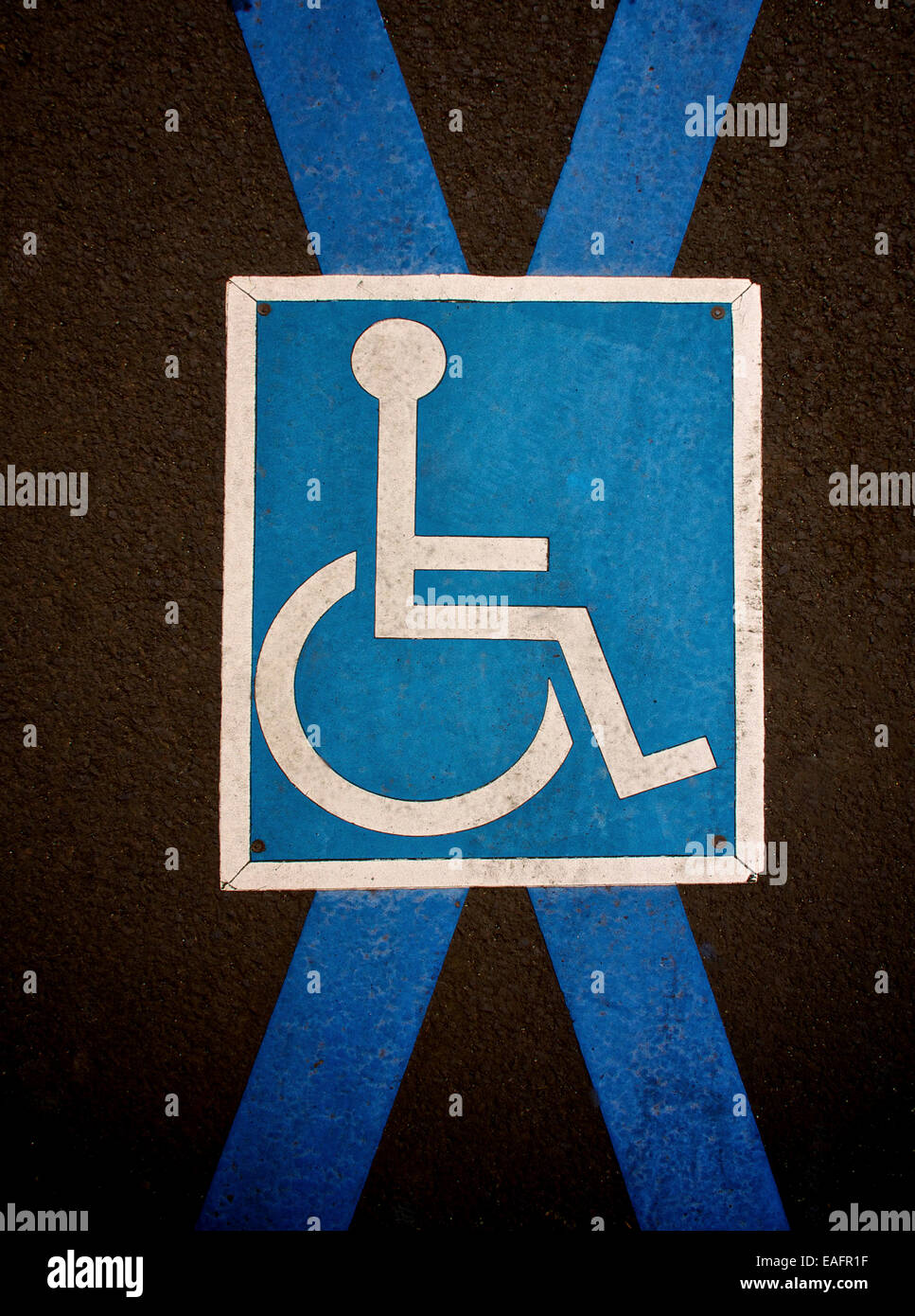 Pictogramme indiquant une place de stationnement pour handicapés sur le trottoir avec un schéma de couleurs bleu et blanc mis en évidence. France. Europe. Banque D'Images