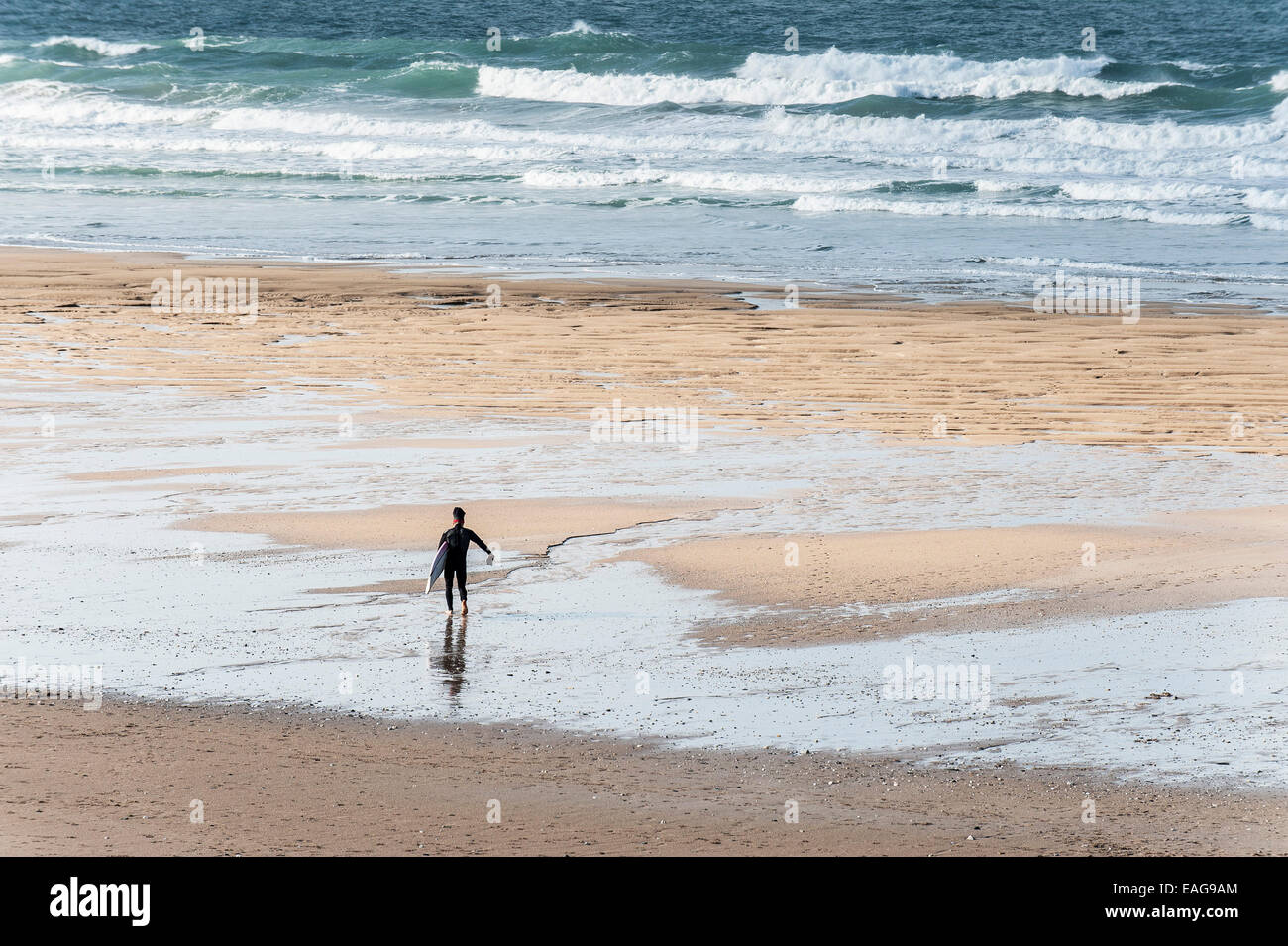 Un surfeur solitaire marcher dehors à la mer sur la plage de Fistral, Newquay, Cornwall. Banque D'Images