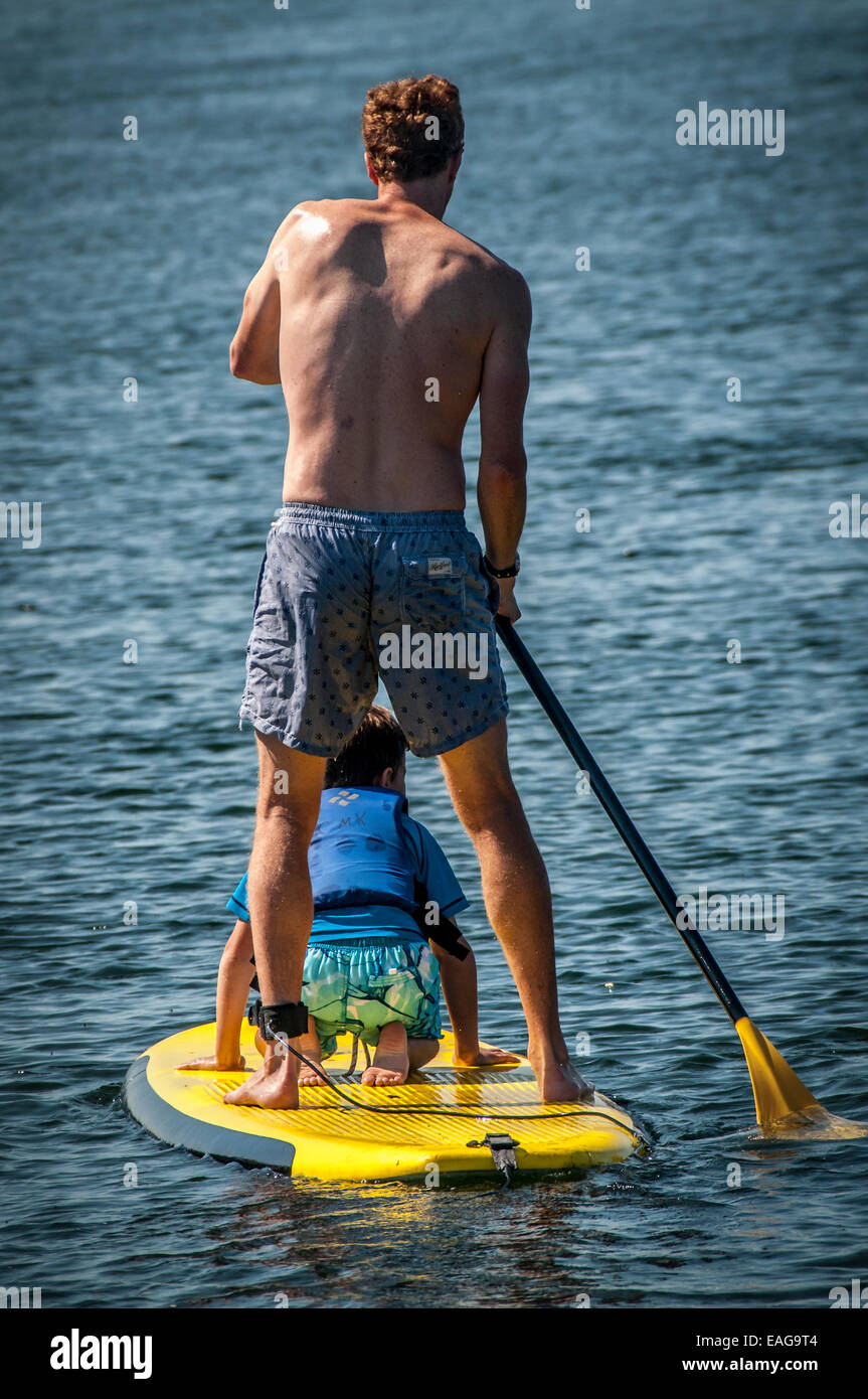 Ce petit garçon est un tour gratuit de son père sur son Paddle Board, comme Papa fait tout le travail la pagaie. Banque D'Images