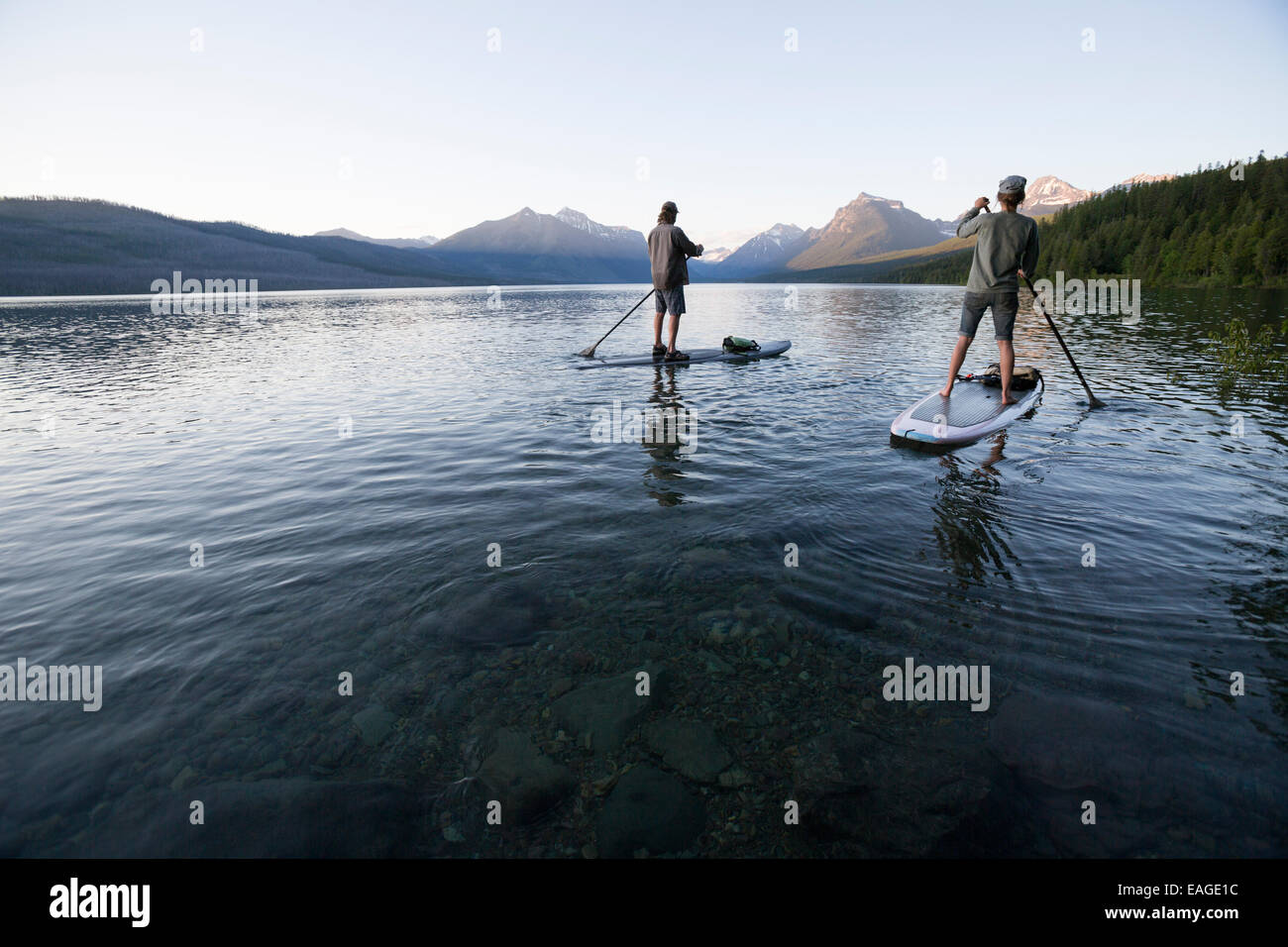 Un homme et une femme en stand up paddle (SUP) sur le lac McDonald dans le parc national des Glaciers. Banque D'Images
