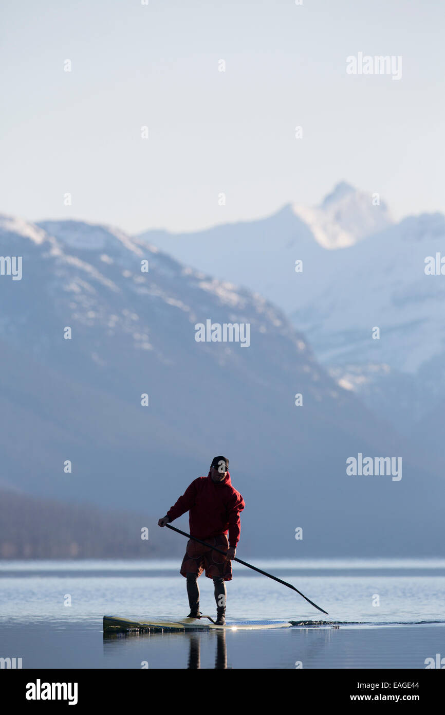 Un homme en stand up paddle (SUP) sur un lac calme McDonald dans le parc national des Glaciers. Banque D'Images