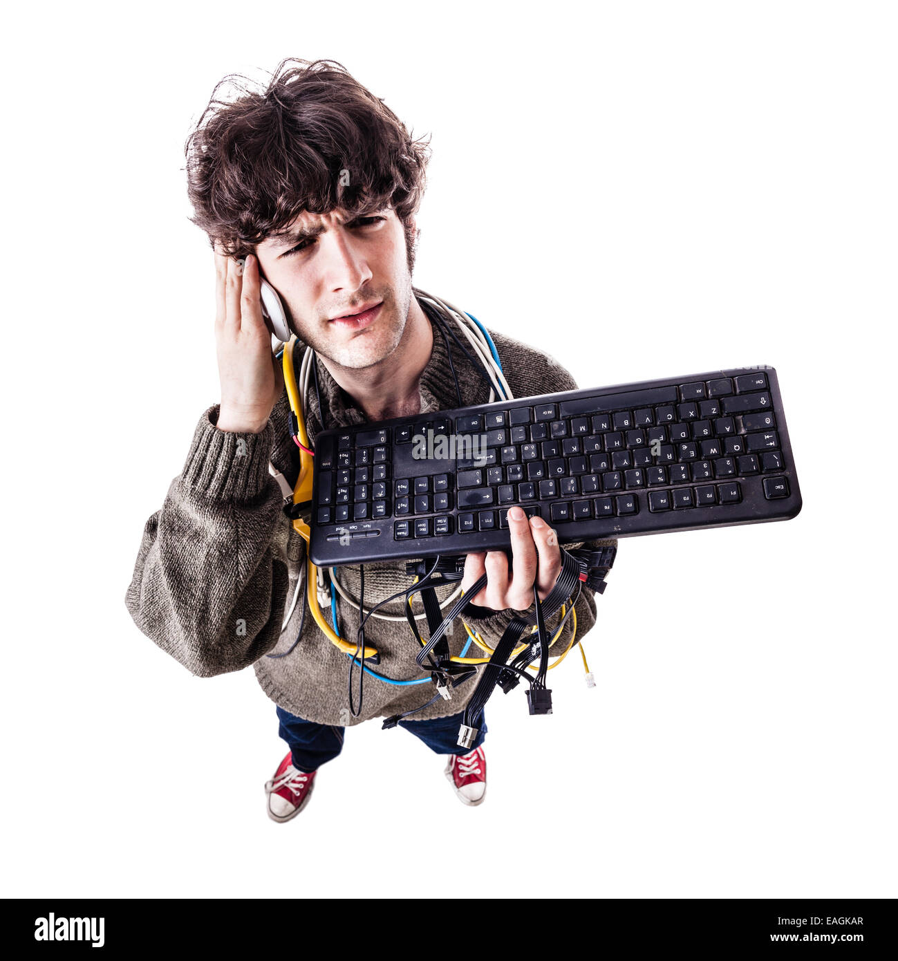 Un mec avec des câbles emmêlés et un clavier struggeling pour obtenir de l'aide de l'ordinateur. isolated on white Banque D'Images