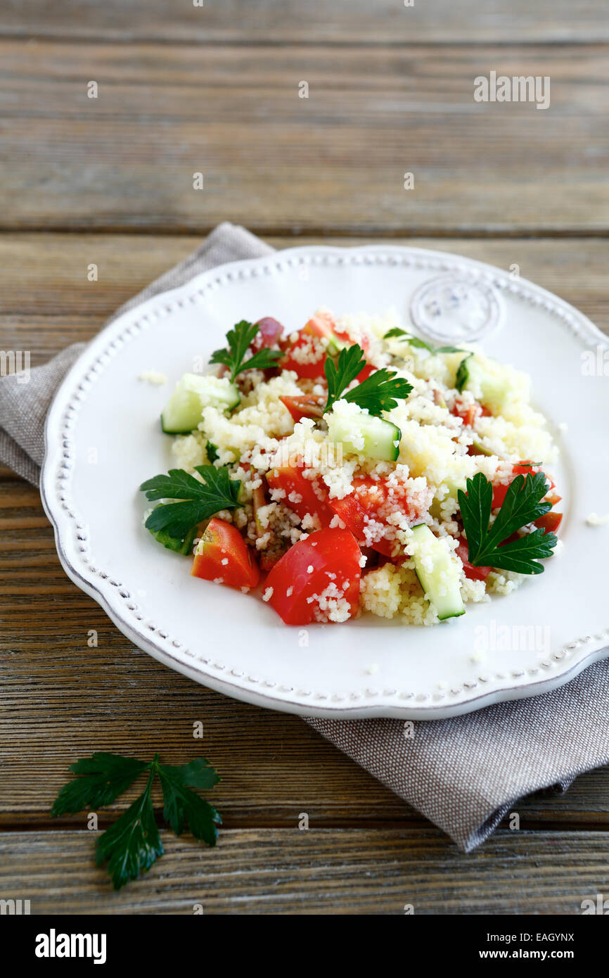 Avec salade de couscous et légumes frais cuits sur une assiette, de l'alimentation sur fond en bois Banque D'Images