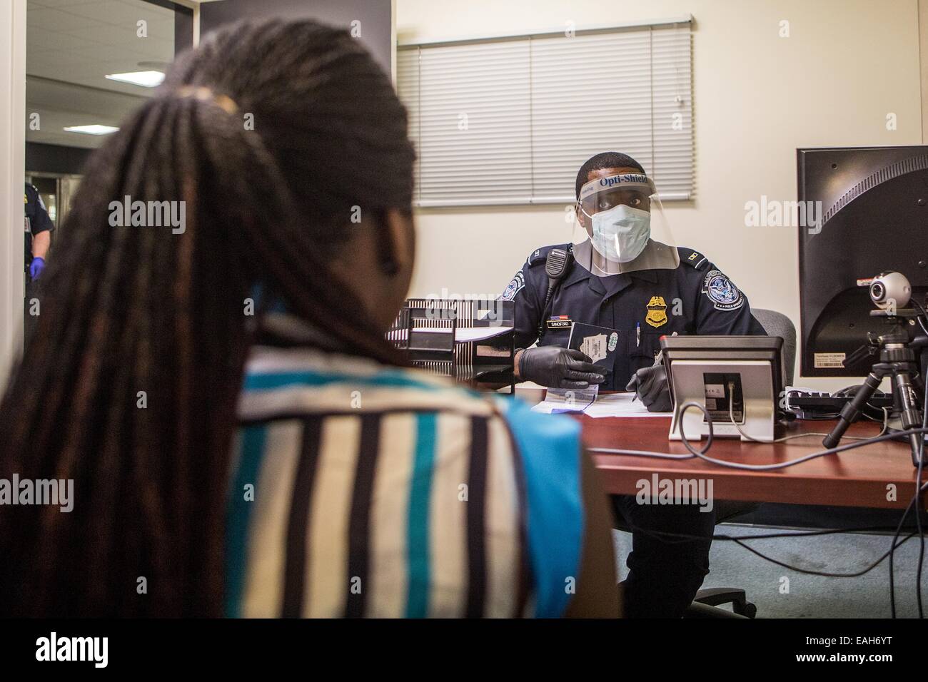 Un agent de l'Immigration américaine procède à une entrevue avec un passager en provenance de l'Afrique de l'Ouest pour contrôler l'infection à virus Ebola à l'Aéroport International de Dulles à Washington le 16 octobre 2014 à Dulles, Virginie. Banque D'Images