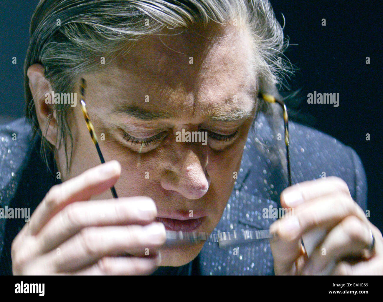 Blixa Bargeld, chanteur du groupe allemand 'Einstuerzende Neubauten, l' ôte son lunettes de lecture après avoir jeté un coup d'oeil sur la set list sur le bord de la scène pendant le concert de Tempodrom à Berlin, Allemagne, 11 novembre 2014. Leur nouvel album 'Lament,' qui est traite de la Première Guerre mondiale, est sorti le 07 novembre 2014. (Culture de remplacement) Photo : Jason Harrell/dpa AUCUN SERVICE DE FIL Banque D'Images