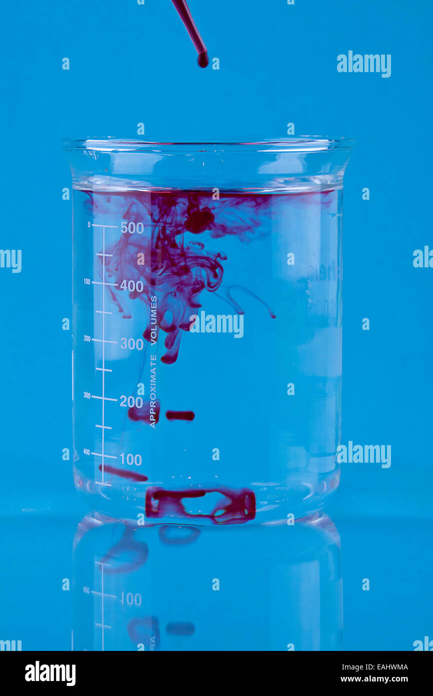 Colorant alimentaire rouge tombé dans un bécher d'eau. Banque D'Images