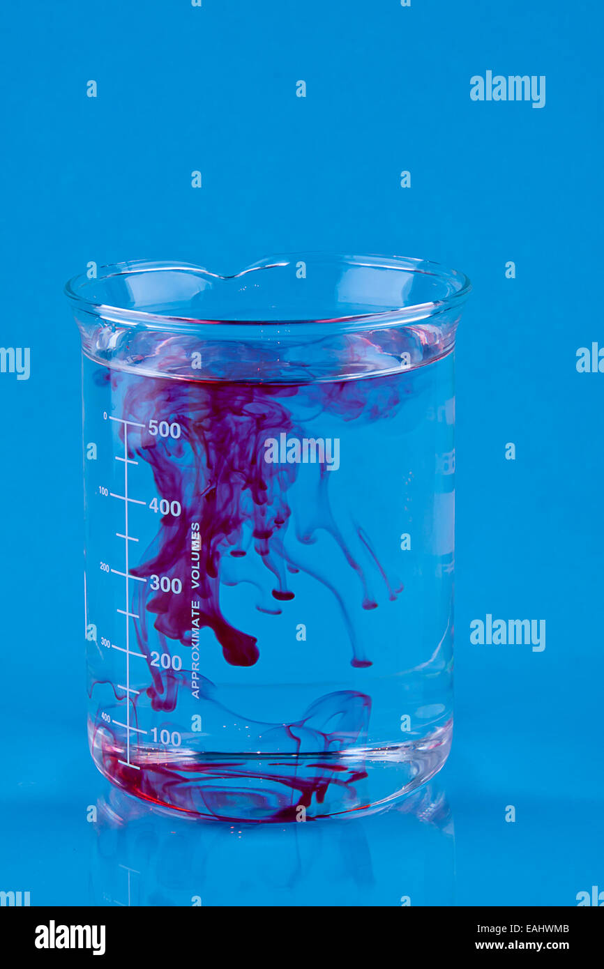 Colorant alimentaire rouge tombé dans un bécher d'eau. Banque D'Images