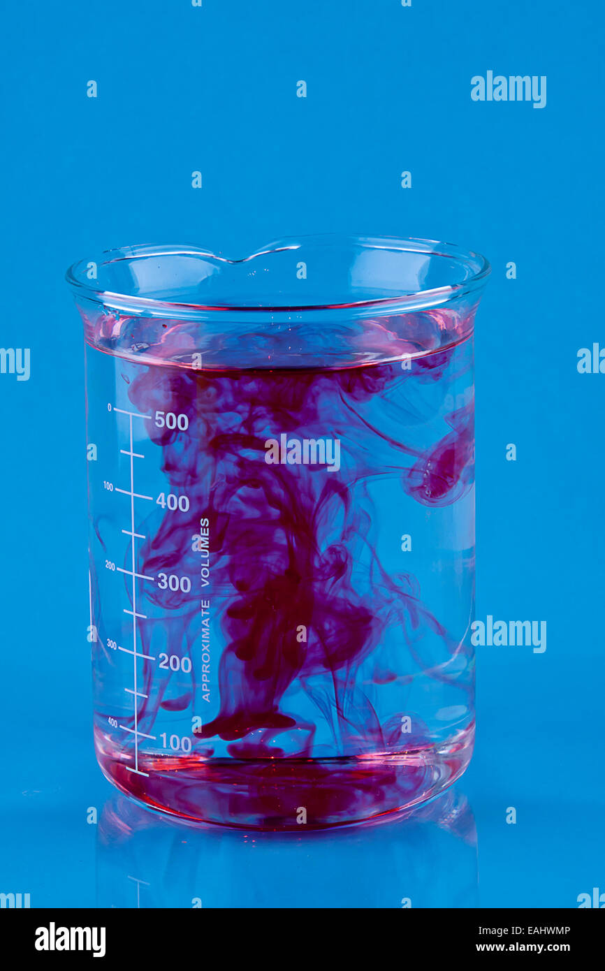 Colorant alimentaire rouge tombé dans un bécher d'eau. Banque D'Images