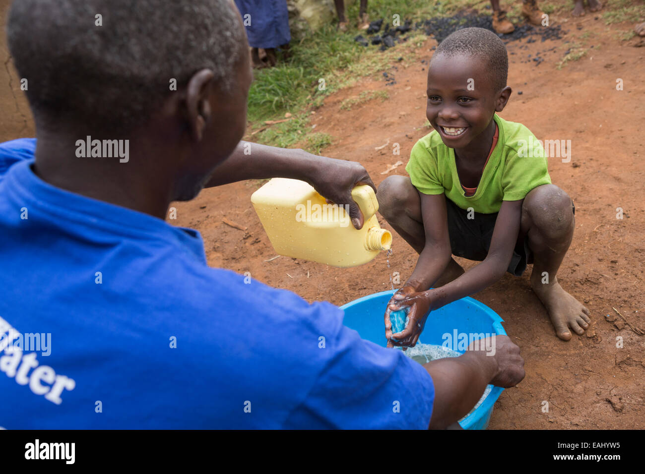 Un garçon se lave les mains avec l'aide d'un travailleur communautaire - Bukwo, District de l'Ouganda, l'Afrique de l'Est. Banque D'Images