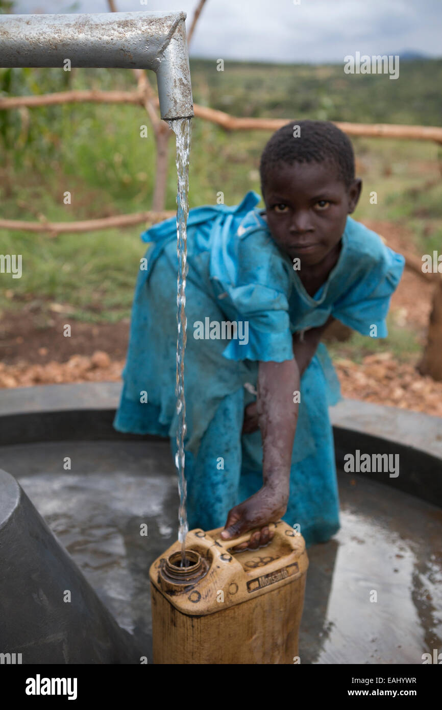 Une jeune fille puise de l'eau d'un puits en Ouganda, District Bukwo. Banque D'Images