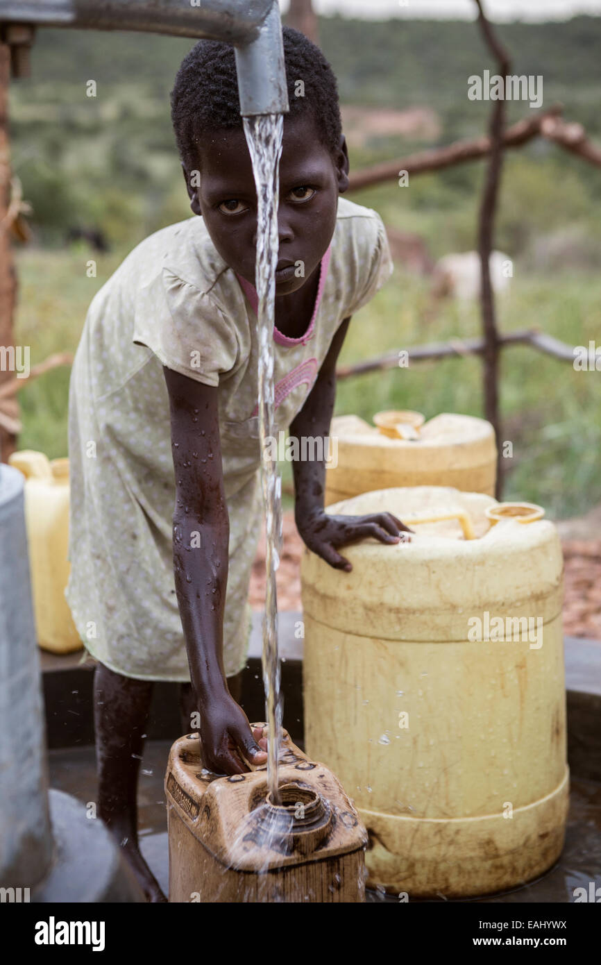 Une jeune fille puise de l'eau d'un puits en Ouganda, District Bukwo. Banque D'Images